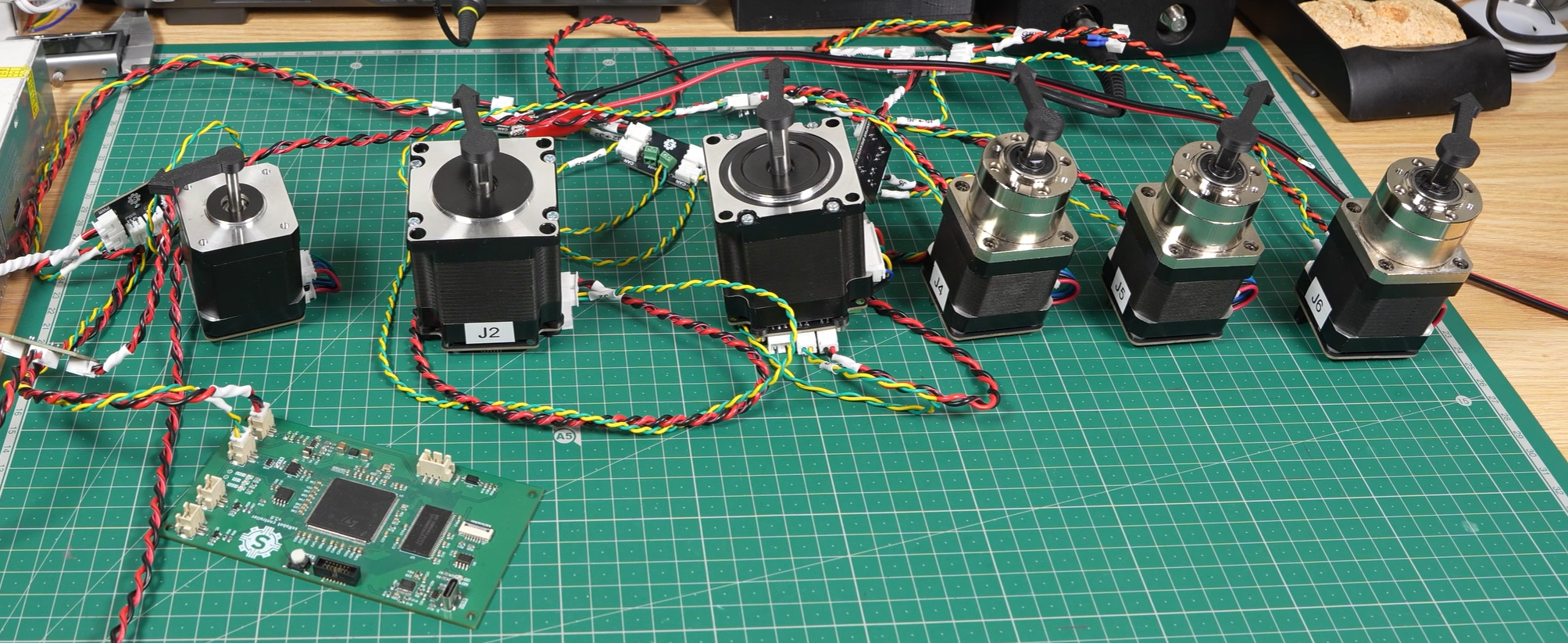 All six stepper motors and their driver boards laid out on a cutting mat
